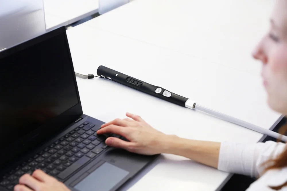 WeWALK Smart Cane 2 - Manufacturer photograph of WeWALK Smart Cane 2 on an office table.