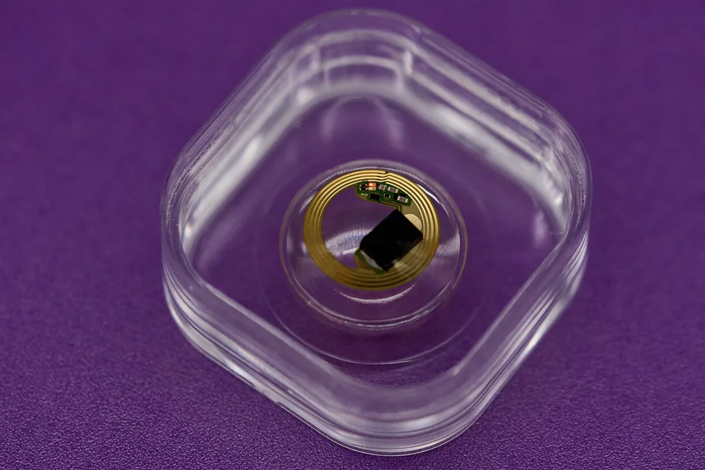 XPANCEO smart contact lens prototype portfolio - XPANCEO photograph of microbattery lens proof-of-concept in a clear holder; a separate technology prototype, not integrated retail AR lenses.